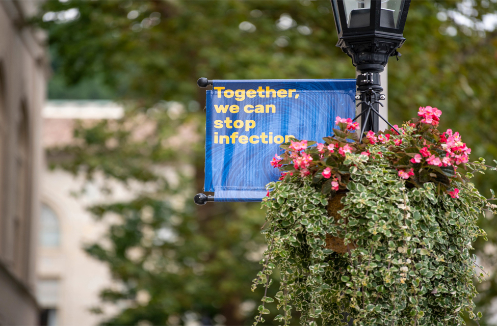 A Power of Pitt sign hangs among Pitt campus landscaping.
